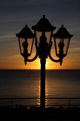 Obraz premium Silhouette of triple outdoor light with the sunset and sea on the background, Ibiza, Spain