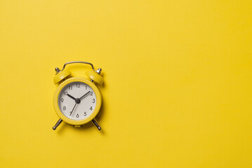 Yellow alarm clock on a yellow background. Copy space. Time concept.