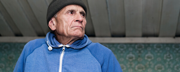 Mature pensioner with sourface wearing knitted cap looking aside