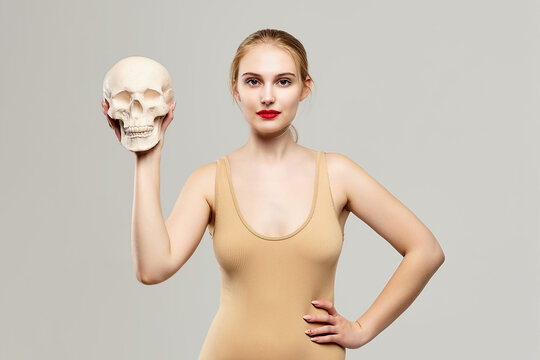 attractive blonde holds a skull in her hands. the concept of photography is suitable in the field of cosmology, medicine and healthcare