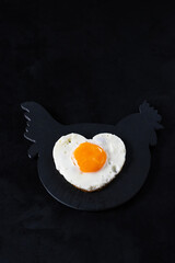 Egg on a dark state cutting board for breakfast on a black background. Creative concept. Low key.