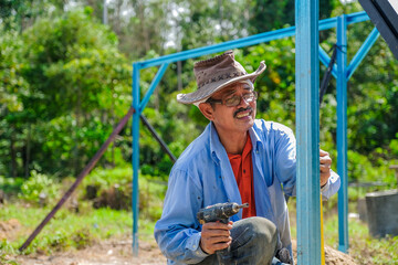 Gardeners use cordless screwdriver and spirit level while building nursery structures from c channel steel in the garden.
