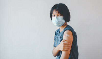 Asian girl showing her arm after getting covid-19 vaccine.