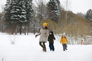 Happy family playing and laughing in winter outdoors in the snow. City park winter day.