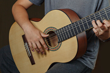 Hands of boy playing an acoustic guitar, close-up. Acoustic guitars are playing. Musical concept. Acoustic guitars. Live music. Boy musician who plays the guitar, musical instrument