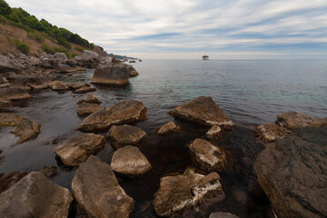 Black Sea, southern coast of Crimea. Quiet evening, calm sea. Large rocks in the salt water in the foreground.