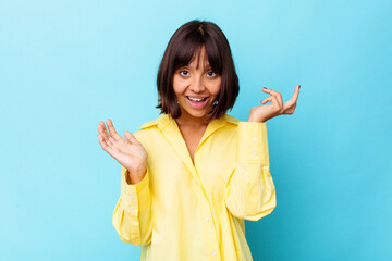 Young mixed race woman isolated on blue background doubting and shrugging shoulders in questioning...
