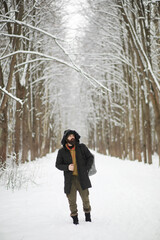 Fototapeta na wymiar Outdoor portrait of handsome man in coat and scurf. Bearded man in the winter woods.