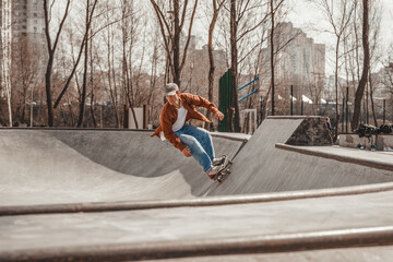 Skater in action in a skatepark in the metropolis rides down on a sloping surface co-focused looking ahead