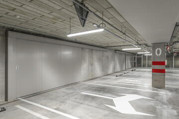 Empty public underground parking lot or garage interior with concrete stripe painted columns and...