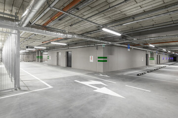 Empty public underground parking lot or garage interior with concrete stripe painted columns and signs