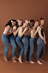 Fototapeta premium Full length of six women with flowers in their hair stands one after another against a brown background
