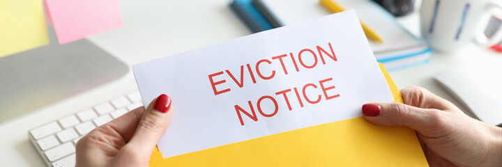 Woman sitting at table and holding eviction letter closeup