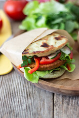 Healthy vegan sandwich with fresh vegetables and a vegan burger inside