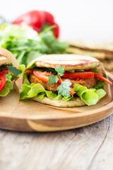 Healthy vegan sandwich with fresh vegetables and a vegan burger inside
