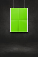 green folded poster hanging on a black wall with clips