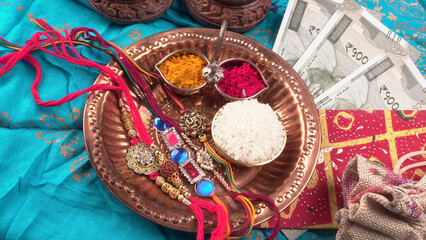 Indian festival: Raksha Bandhan background with an elegant Rakhi, Rice Grains and Kumkum. A traditional Indian wrist band which is a symbol of love between Brothers and Sisters.
