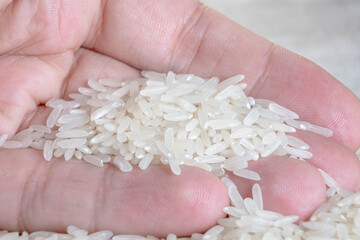 A male hand holding a pile of dry white rice. Organic natural food, health care.