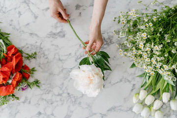 Female hands holding white flower above marble table - Powered by Adobe
