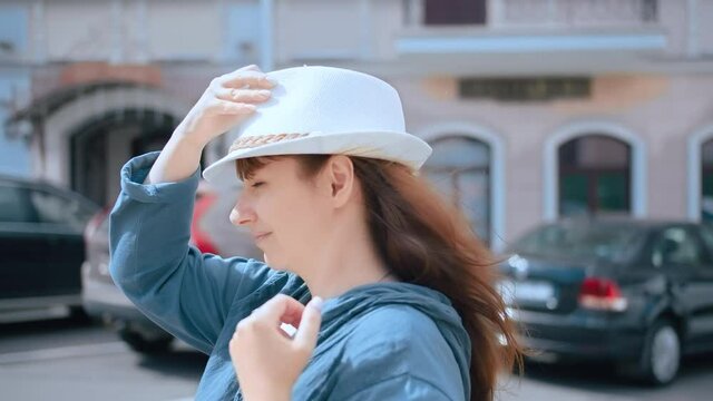 pretty brunette woman wearing hat outdoors, woman straightens her hair and puts on a hat, slow motion, cinematic shot