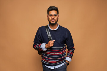 Young bearded hindu student with backpack on pastel background