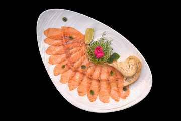 Salmon carpaccio on plate isolated on black background