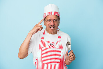 Senior indian ice cream man holding a scoop isolated on blue background showing a disappointment gesture with forefinger.