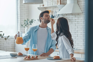 Beautiful young couple enjoying breakfast together while spending time in the domestic kitchen