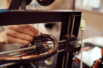 Crop man inserting plastic coil into 3D printer