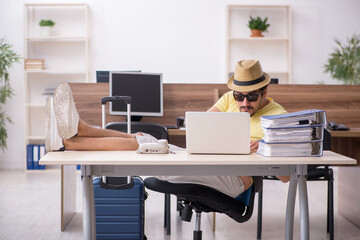 Fototapeta premium Young male employee preparing for trip at workplace
