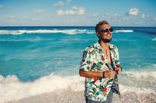 Fototapeta Handsome happy man wearing hawaiian shirt at the sea or the ocean background. Travel vacation holiday. Man walking at the sea, enjoy tropical season