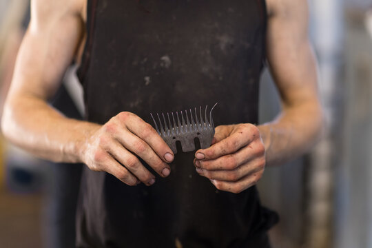 shearing comb being held in shearer's dirty hands