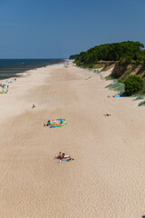 tourists relaxing on the beach, walking and sunbathing.