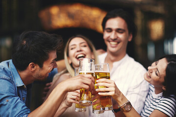 Group of young people at a summer bar toast with beer. Selective focus on beer.
