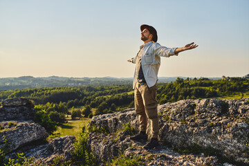 Young man enjoying summer hiking standing with arms spread open