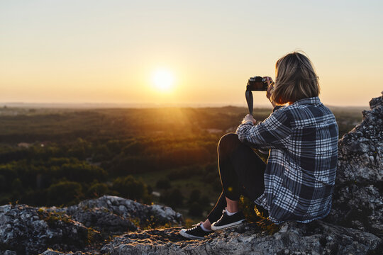 Woman photographing sunset with camera while in the mountains
