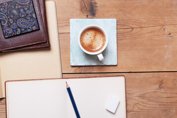 Cup of coffee with notebook on wooden background.