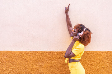 Chica afro escuchando música con una mano levantada y con espacio para texto.