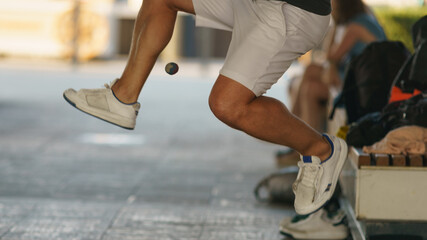 A young athlete fulfills its footbag tricks. Footbag freestyler practices on the Moscow city street. Game with small ball is very popular among youth. Active healthy lifestyle concept.