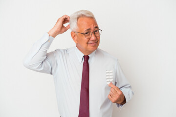 Senior american man holding pills isolated on white background being shocked, she has remembered...