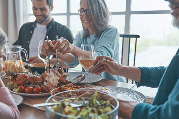 Happy multi-generation family holding hands and praying before having dinner