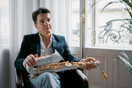 Portrait of an adult male music teacher playing the saxophone.