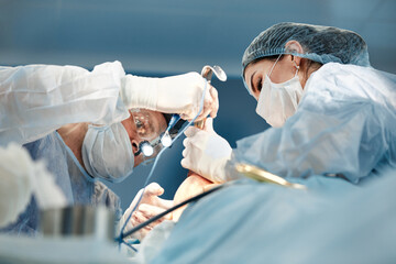 Close up of doctors and nurses in operating room, professional doctors during work in modern operating room, plastic surgery concept
