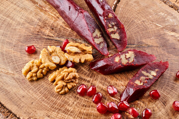 slicing Churchkhela, pomegranate and nuts on a wooden background, top view, serving