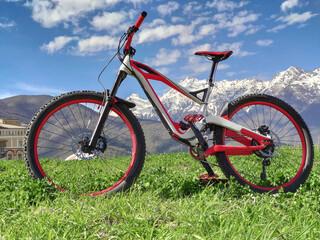 Full suspension bicycle for downhill riding on grass at snowy mountains background