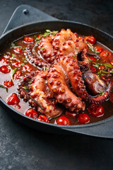 Traditional Italian polpo alla griglia in salsa di pomodoro with barbecued octopus in tomato sauce served as close-up on a modern design saucepan