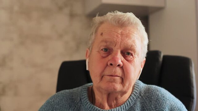 elderly woman grandmother putting on headphones close-up.