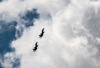 a group of combat aircraft perform complex aerobatics with a smoke launch against the sky