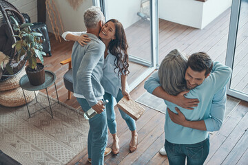 Top view of happy senior parents meeting young couple inside the house