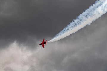 the red plane makes a difficult turn leaves a white trail of flight against the background of the...